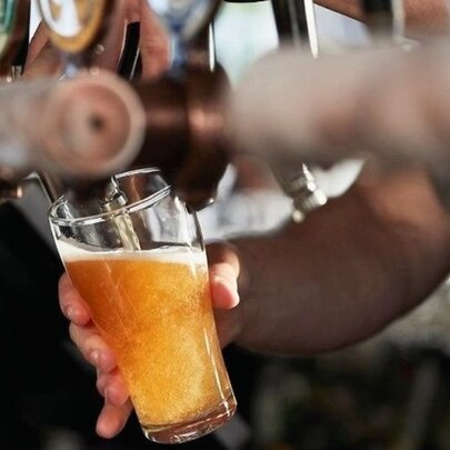Glass of beer being poured from a tap in a bar.