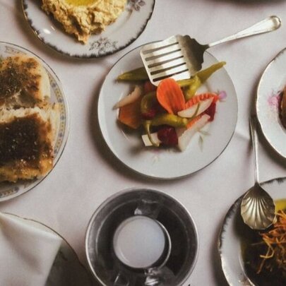 Looking down at a spread of Turkish meze plates, including hummus, pickled vegetables, and pide bread.