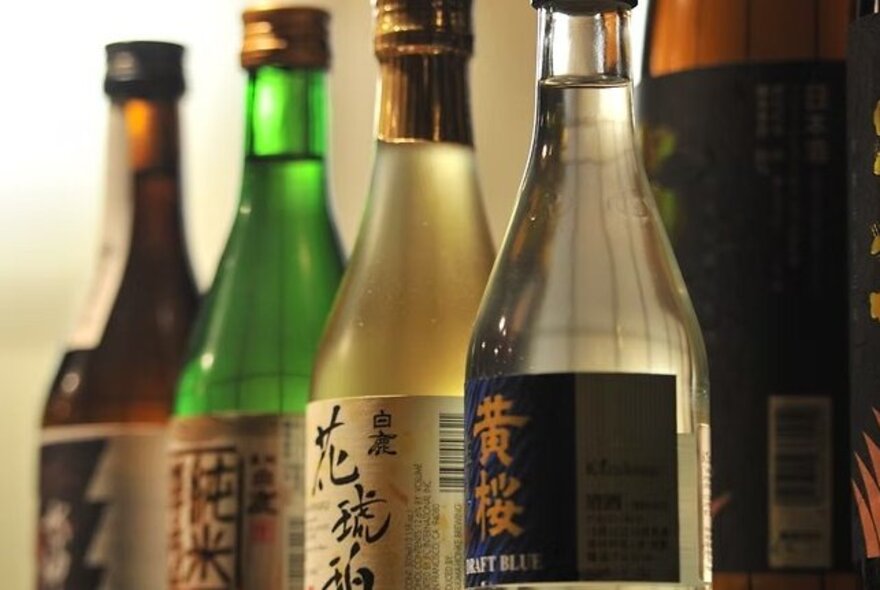 Four neatly lined up bottles of Japanese sake.