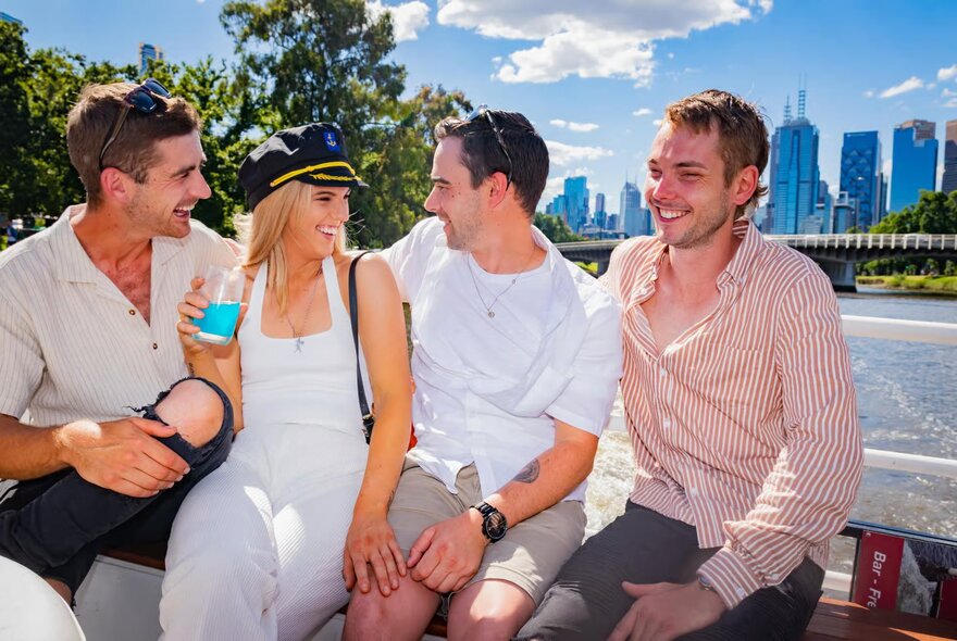 Four people on a Yarra River cruise boat, the woman wearing a captain's hat. 