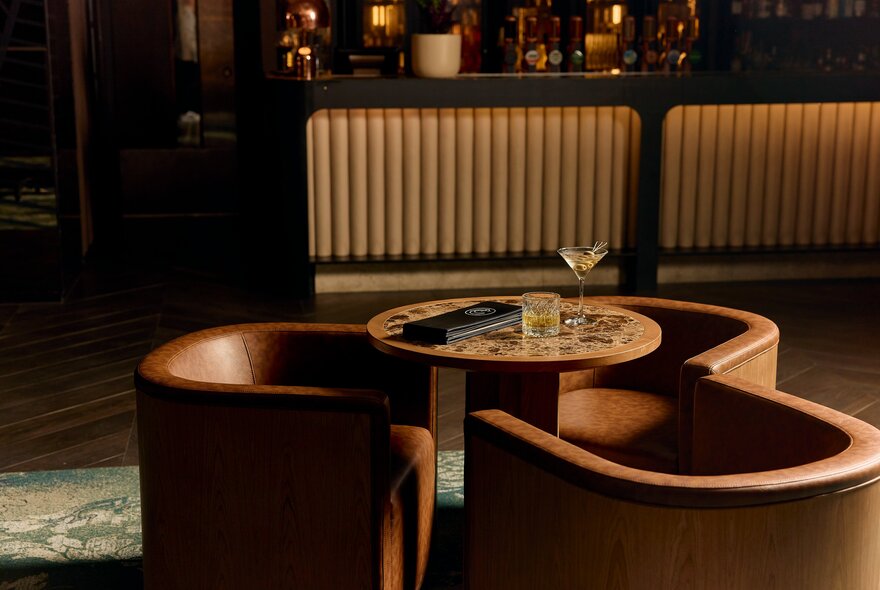 Interior of The Cliveden Bar & Dining at the Pullman East Melbourne, featuring elegant curved leather chairs and a textured bar front.