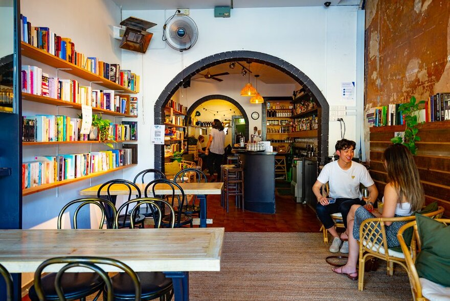 A couple in a casual bar with book shelves lining the walls.