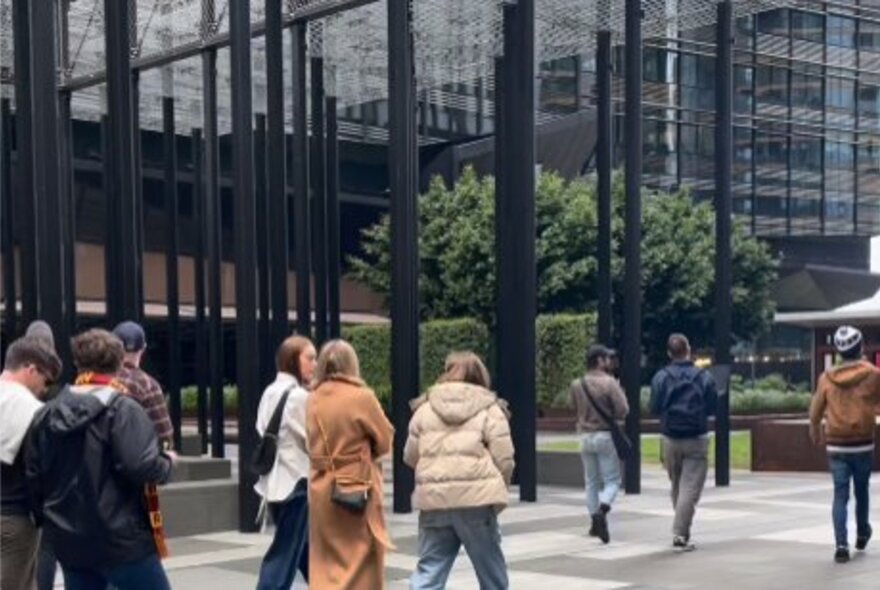 Tour group walking past a city building on a Melbourne street.