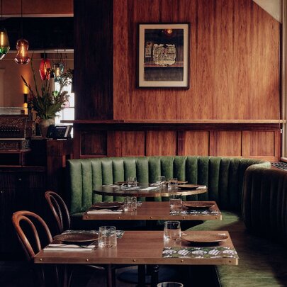 Comfortable banquette seating around tables in a wood panelled interior of a restaurant.