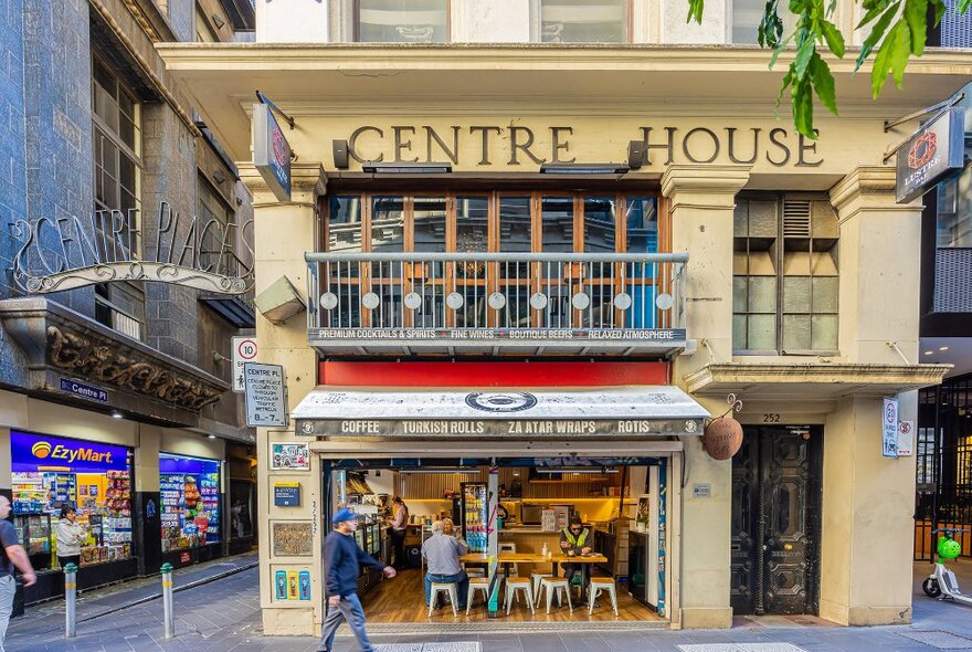 A cafe with seating on the corner of a laneway. 