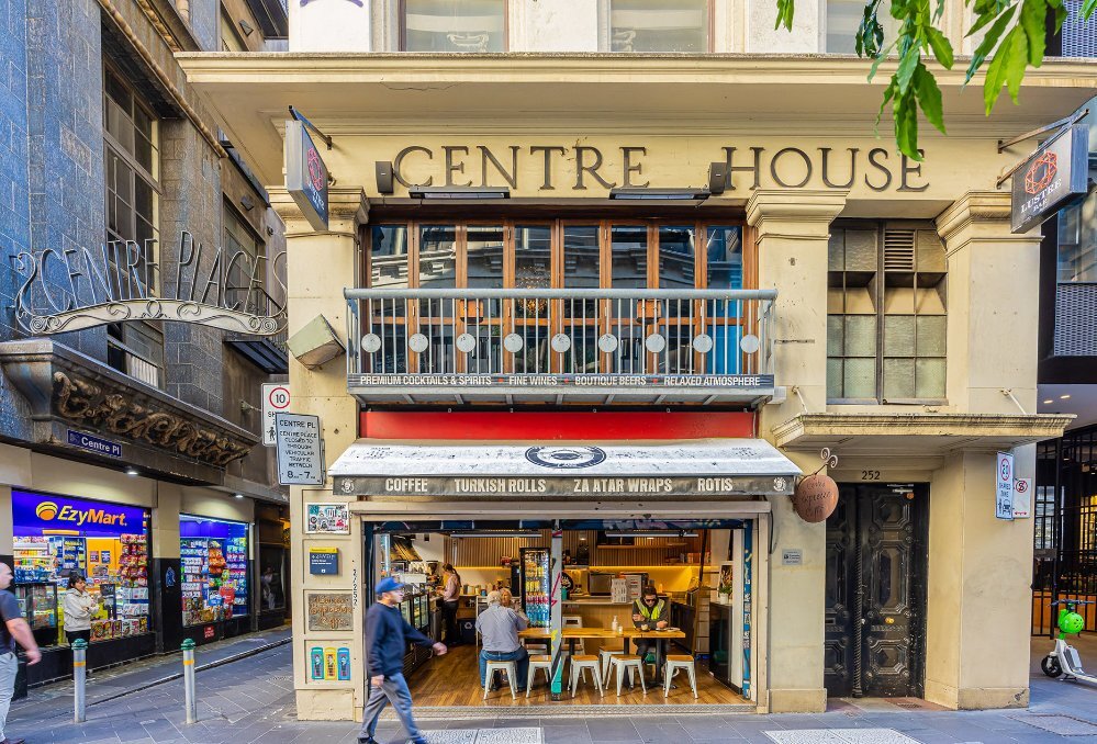 A cafe with seating on the corner of a laneway. 