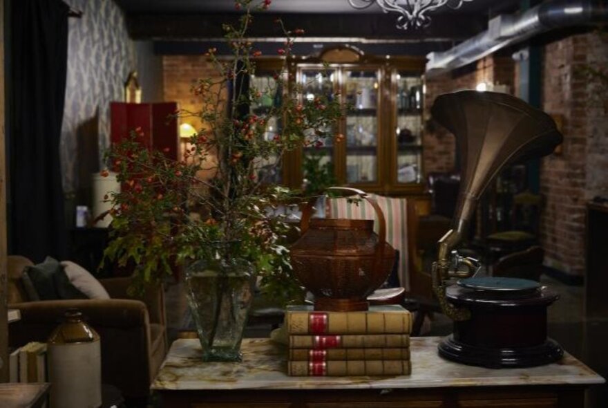 Cellar bar with vintage props including books, gramophone and lamplight.