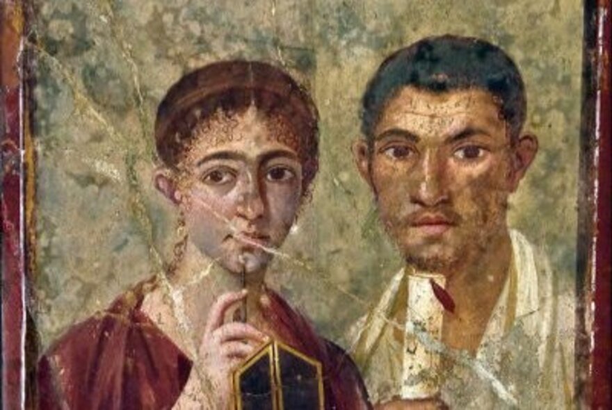 Ancient Roman wall mural of a man and a woman holding papyrus scroll and pen.