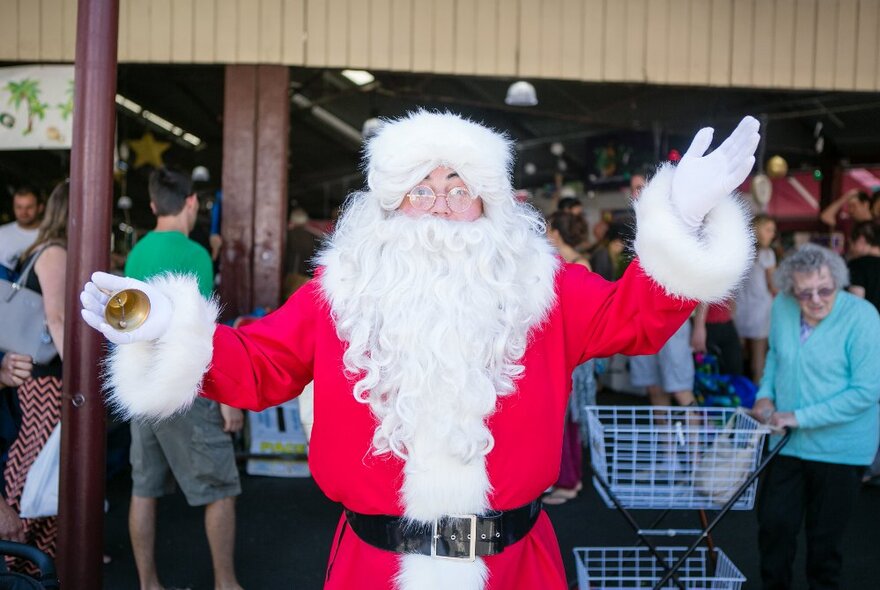 Santa Claus waving his hands in the fresh produce stands at Queen Victoria Market.