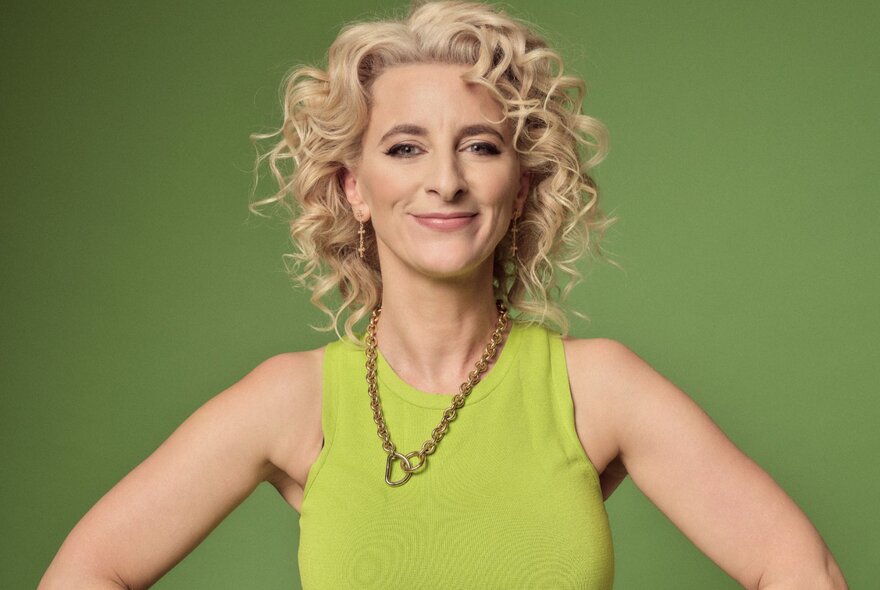Woman with curly blonde hair, her hands on her hips, wearing a lime tanktop.