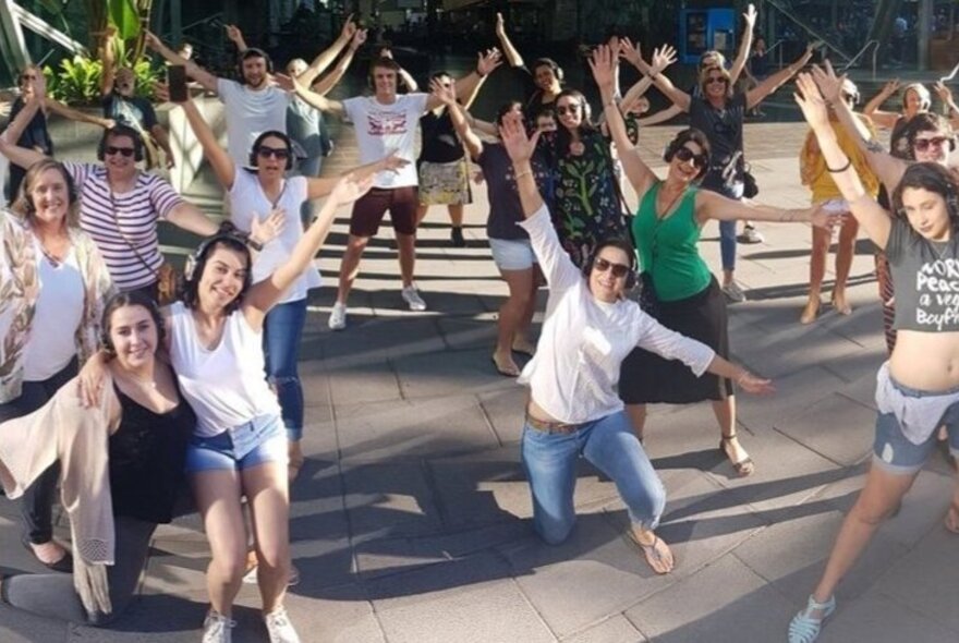 Tour participants posing with arms and legs outstretched in a public space.