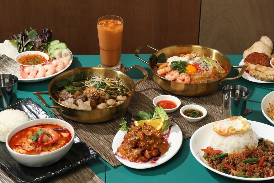 A selection of Thai dishes served on platters and plates on a restaurant dining table.