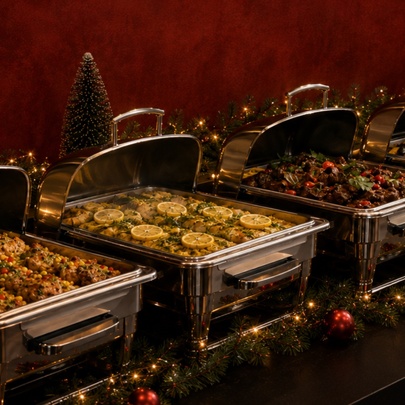 A hotel buffet with a line of bain-marie with lids open against a deep red background. 