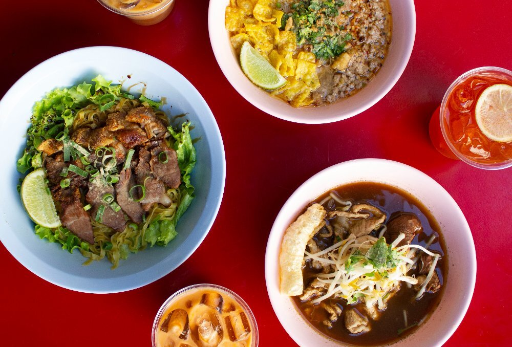 Aerial view of three noodle bowls and three drinks.
