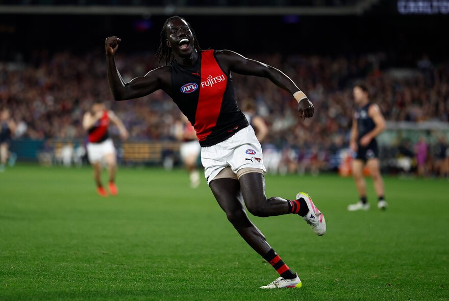 Essendon AFL football player with arms outstretched during a match.
