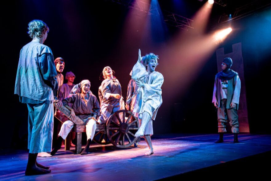 Actors performing and dancing on stage in peasant dress.