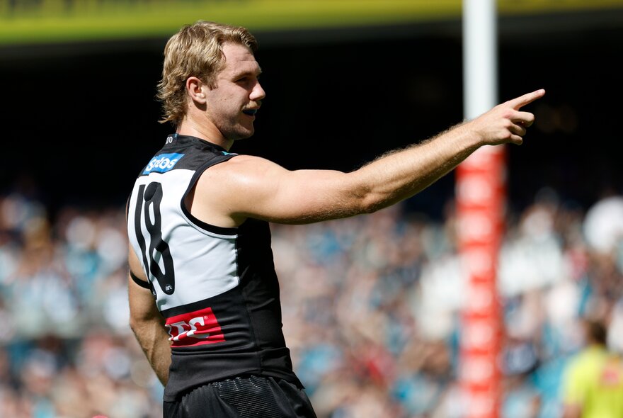 A Port Adelaide AFL football player with his arm pointing towards the goals during a match.