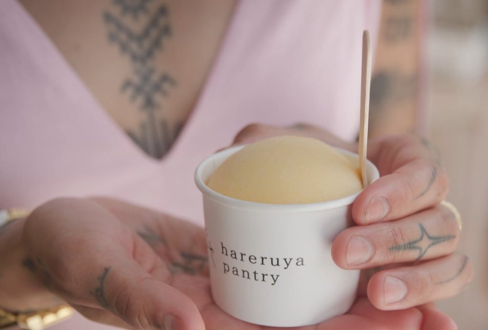 A cup of mochi wrapped ice cream held by a women with tattoos.