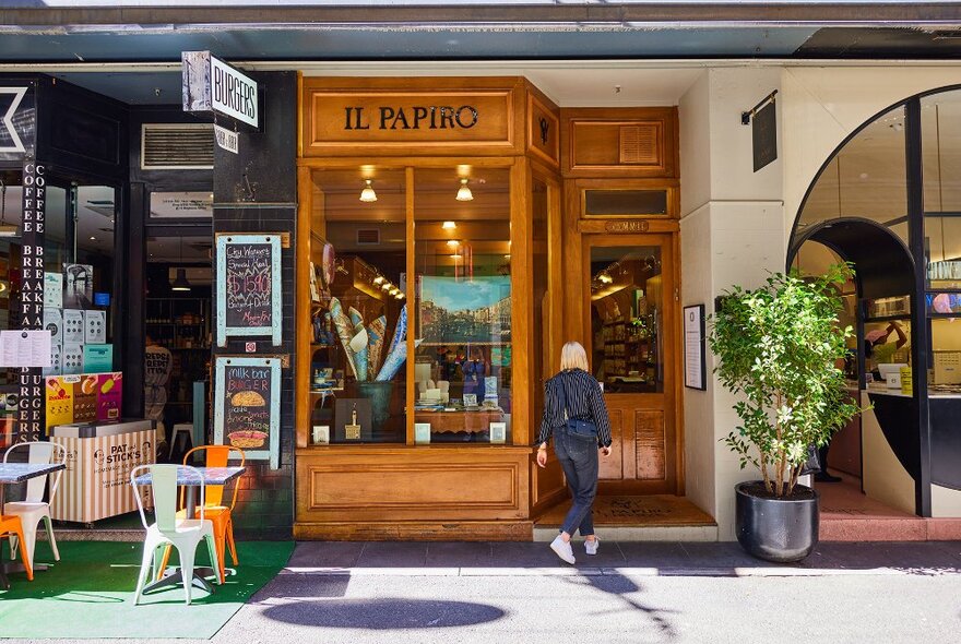 A blonde woman walking into a narrow store with an old-fashioned timber exterior. 