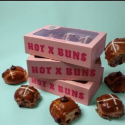 Box of branded hot cross buns, surrounded by buns.