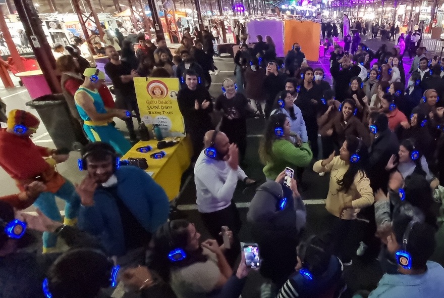 A large group of people dancing in a crowd at Queen Victoria Market.