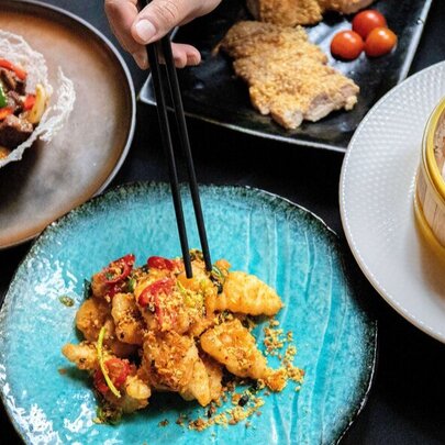 Array of Asian tasting dishes on a table with chopsticks.