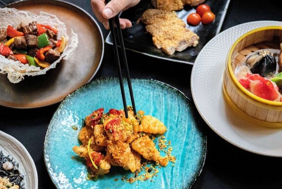 Array of Asian tasting dishes on a table with chopsticks.