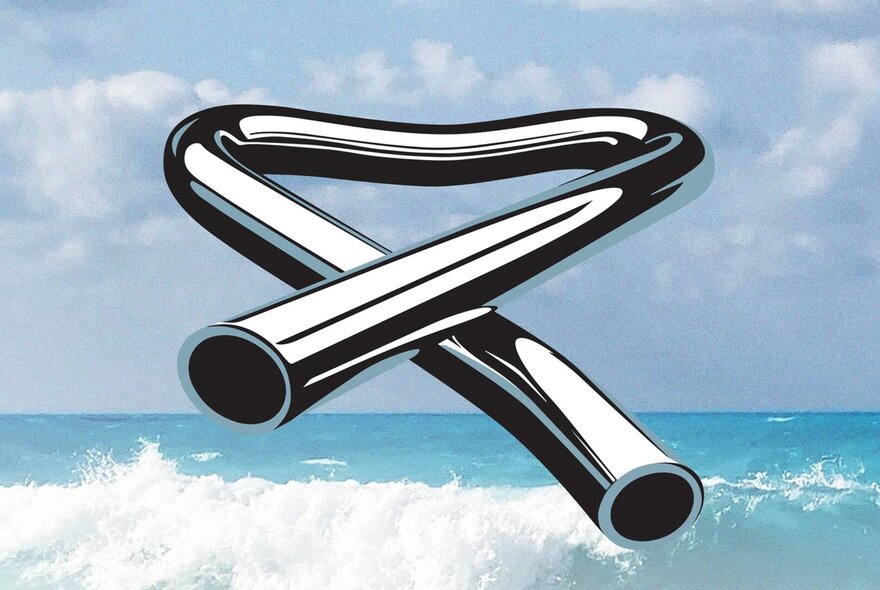 The album cover for Mike Oldfield's Tubular Bells features a large, shiny, bent metal tube in a twisted shape, against a background of a blue sky with white clouds and an ocean with white-capped waves crashing.