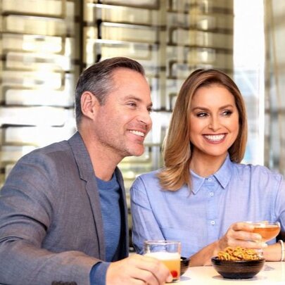 A smiling and well groomed couple at a bar enjoying a cocktail.