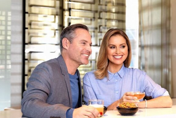 A smiling and well groomed couple at a bar enjoying a cocktail.
