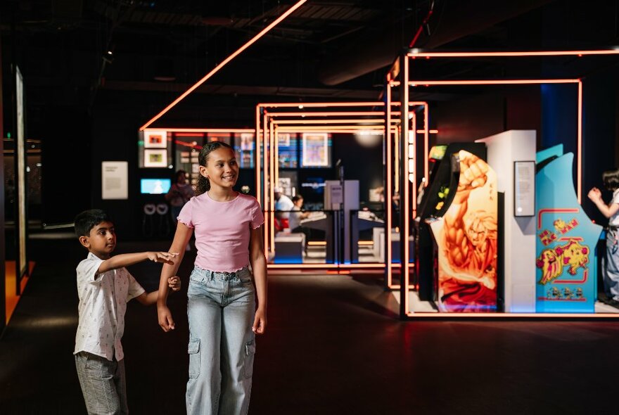 Two children exploring an exhibition in a dark room. 