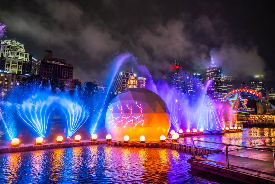 Laser lights and Christmas bauble installation illuminating the Yarra River at night.