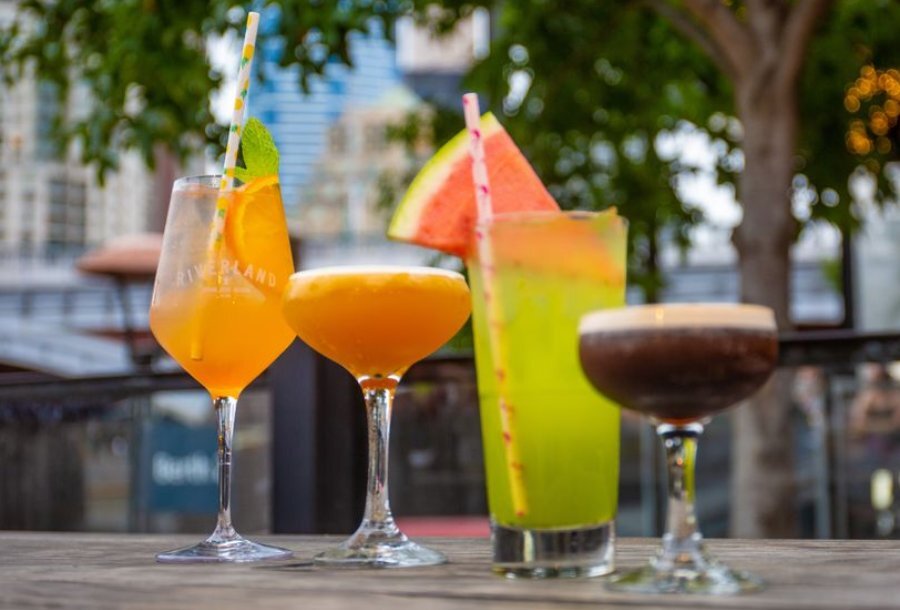 Four colourful cocktails outside a bar