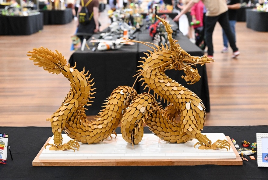 Chinese dragon made from Lego blocks on a plinth on a table.