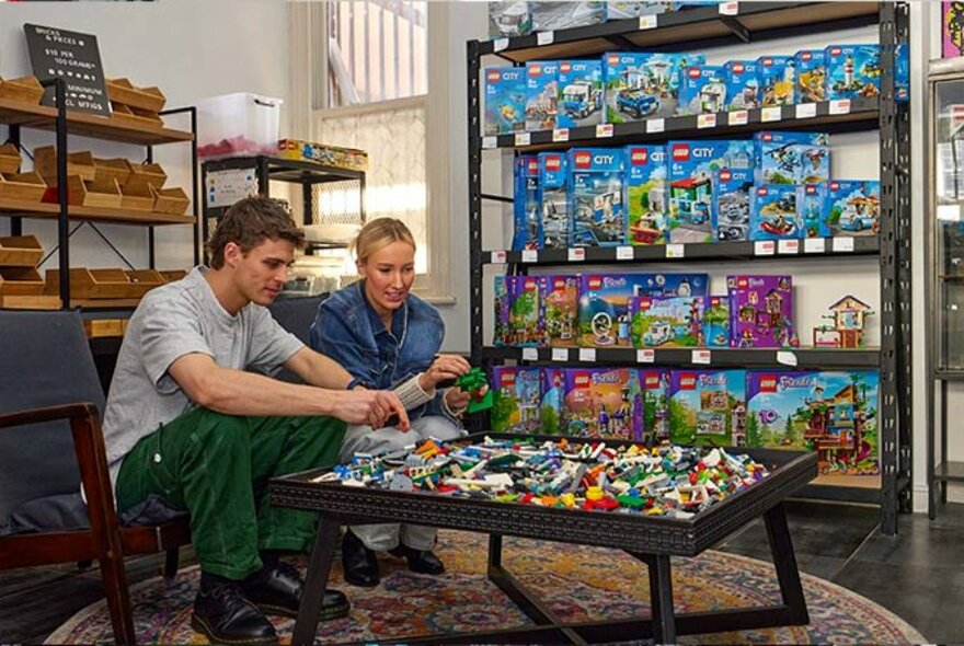 Two people assembling Lego bricks in a store.