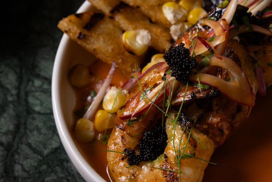 A seafood bisque with a whole prawn, seen from above.