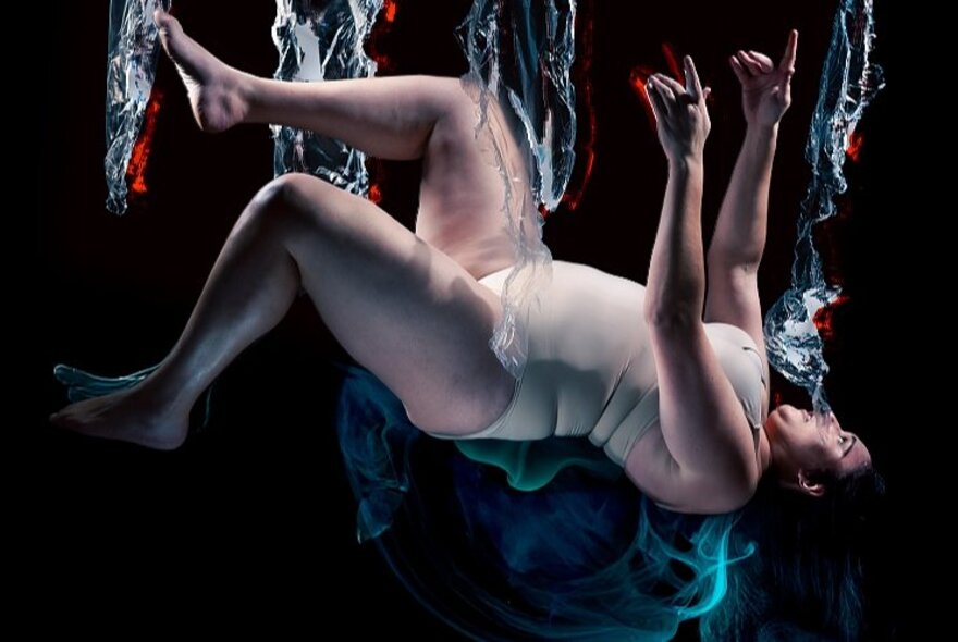 A human in a skin-coloured leotard floating in a dark space with streams of vertical water surrounding them.