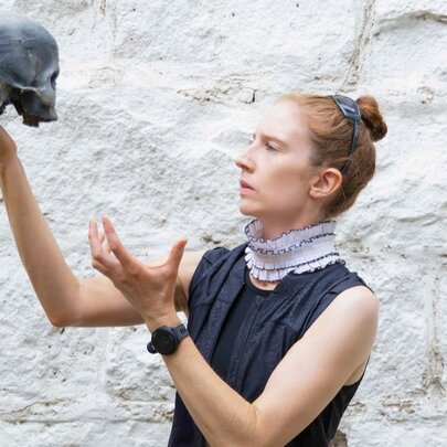 Actor playing Hamlet, holding a skull and gesturing.