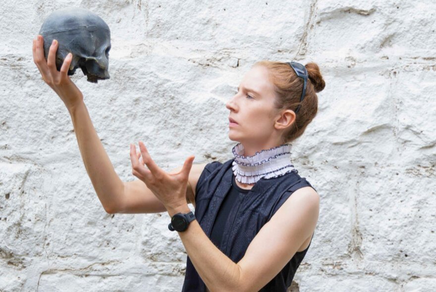 Actor playing Hamlet, holding a skull and gesturing.