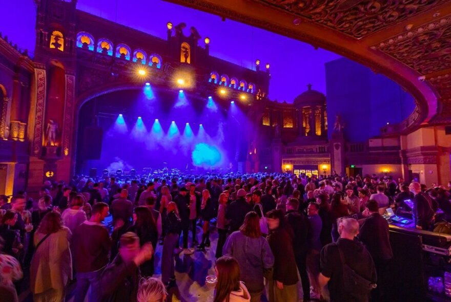 A stage with a grand facade to look like a building, with crowds waiting for a band to come on stage.