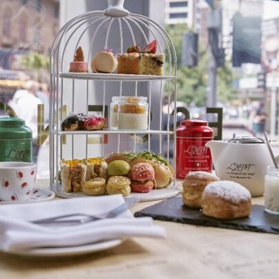 A selection of sweet and savoury small food items as part of a high tea, arranged on a linen covered table.