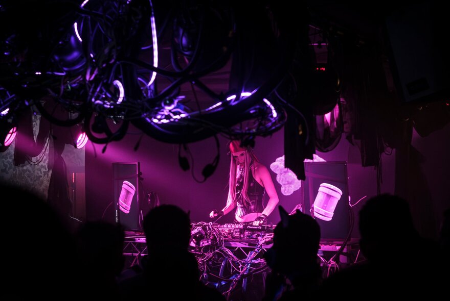 A DJ playing music with purple spotlights on her.