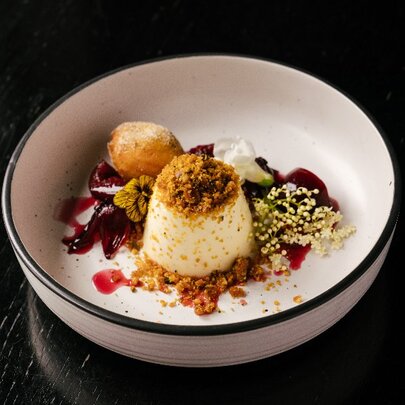 A dessert dish with panna cotta, ice cream and garnishes.