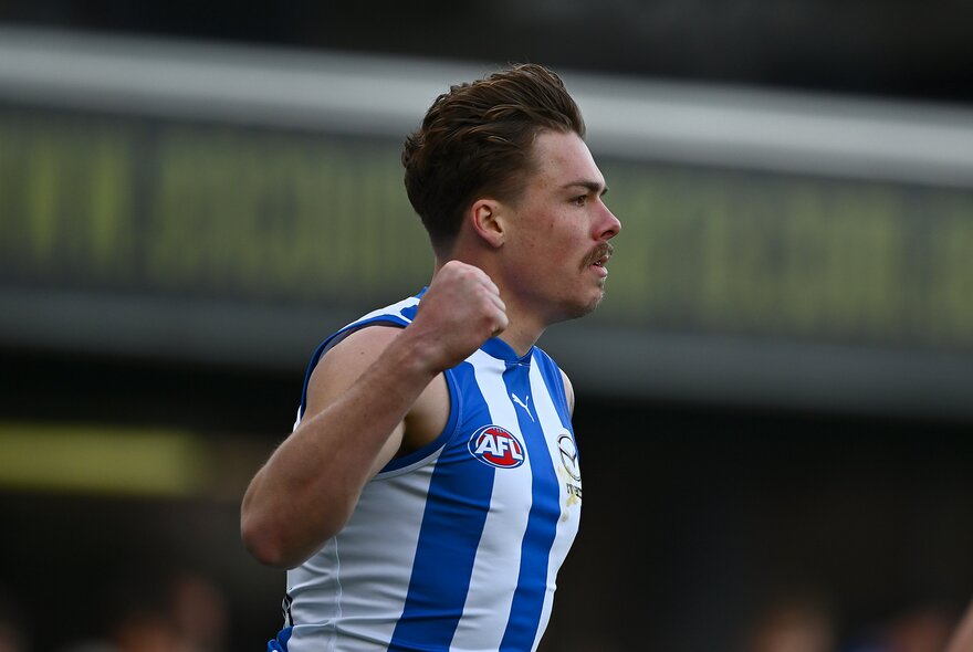 North Melbourne AFL football player with arm outstretched during a match.