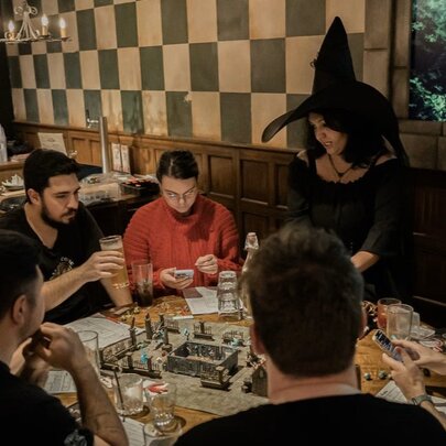A group of friends playing the board game dungeons and dragons at Fortress Tavern Melbourne, with a Dungeon Master dressed in a witch's costume leading the game.