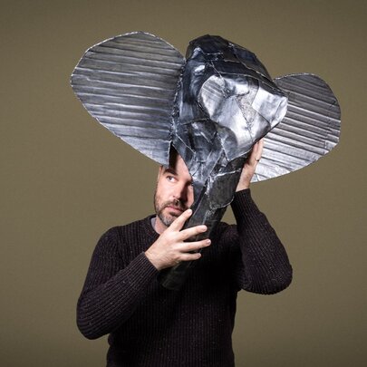 A man balancing a sculpture of an elephant on his head.