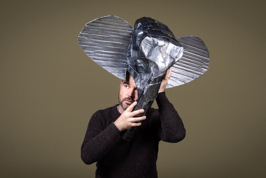 A man balancing a sculpture of an elephant on his head.