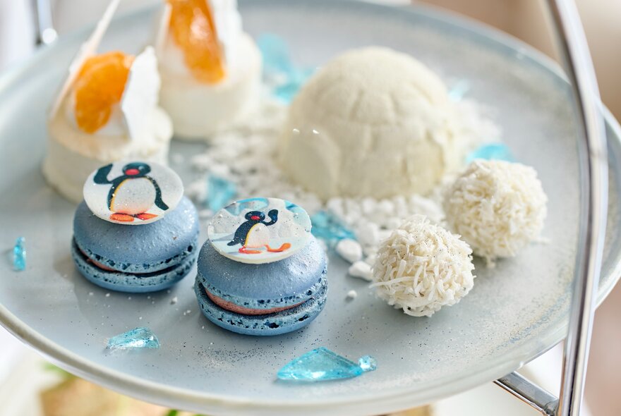 Afternoon tea plate with Pingu-themed blue macarons and white cakes. 