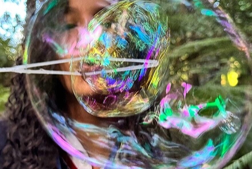 Face reflected in an iridescent bubble.