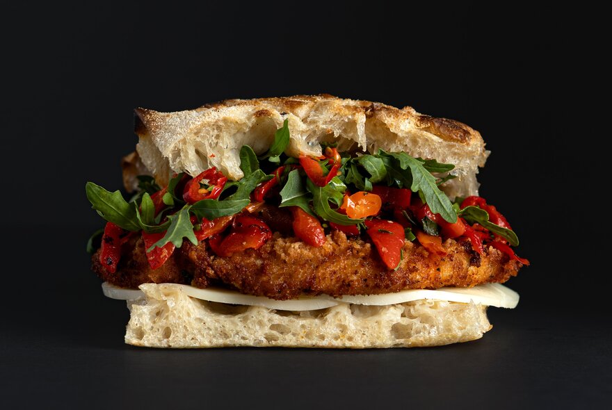 Saluministi panino featuring crumbed chicken, roasted peppers, cheese and rocket in focaccia bread.